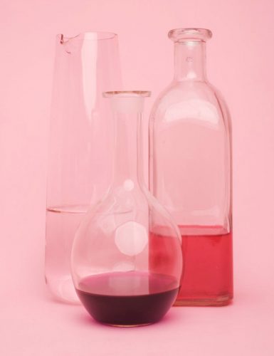 3 glass beakers and vases with different amounts of red liquid in