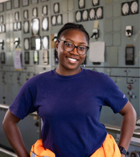 A photo of Jenn, with a hi viz jacket round her waist in a power station.