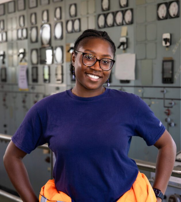 A photo of Jenn, with a hi viz jacket round her waist in a power station.