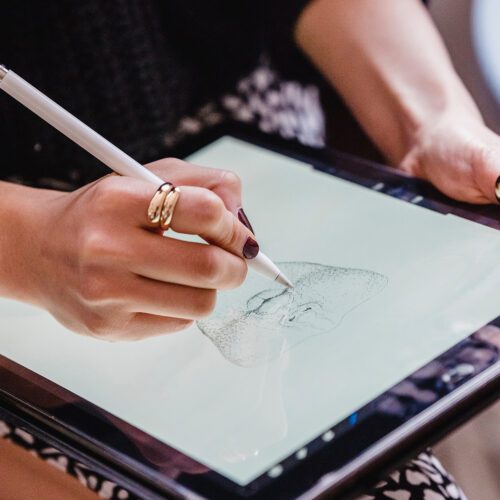 Woman's hand drawing a man's face on an iPad