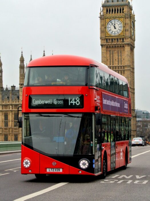 A London bus driving over Westminster bridge, with Big Ben in the background.