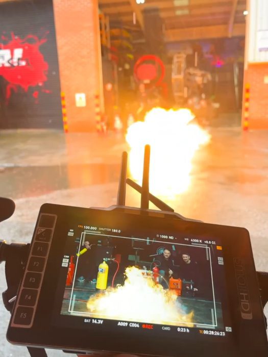 A video camera capturing live flames on a film set.
