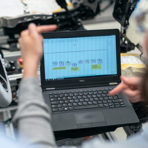 Person working on laptop and gesturing in front of screen