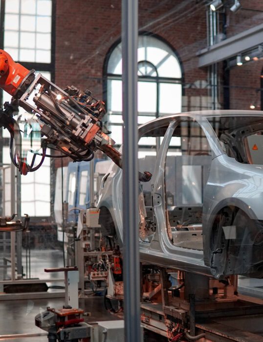 Empty frame of a car being painted by a robotic machine