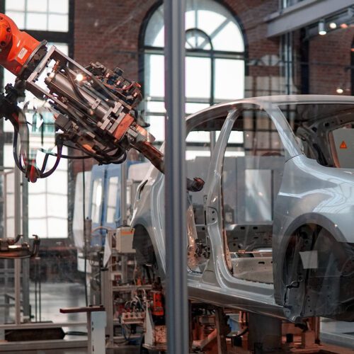 Empty frame of a car being painted by a robotic machine