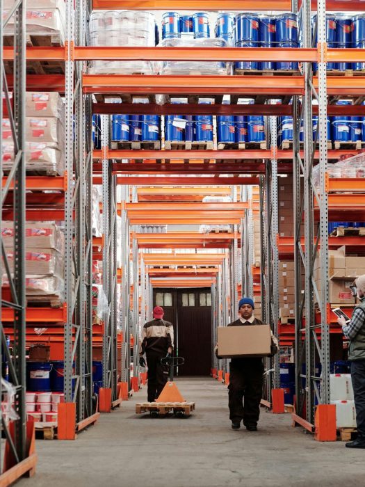 Two members of staff walking though a warehouse of goods.