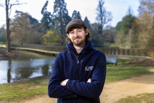 Charlie standing in Kew Gardens, next to a path, trees and a lake