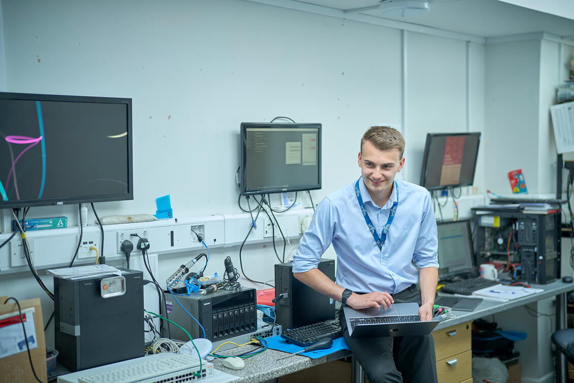 Cyber Technician in an office surrounded by lots of computers and electrical devices