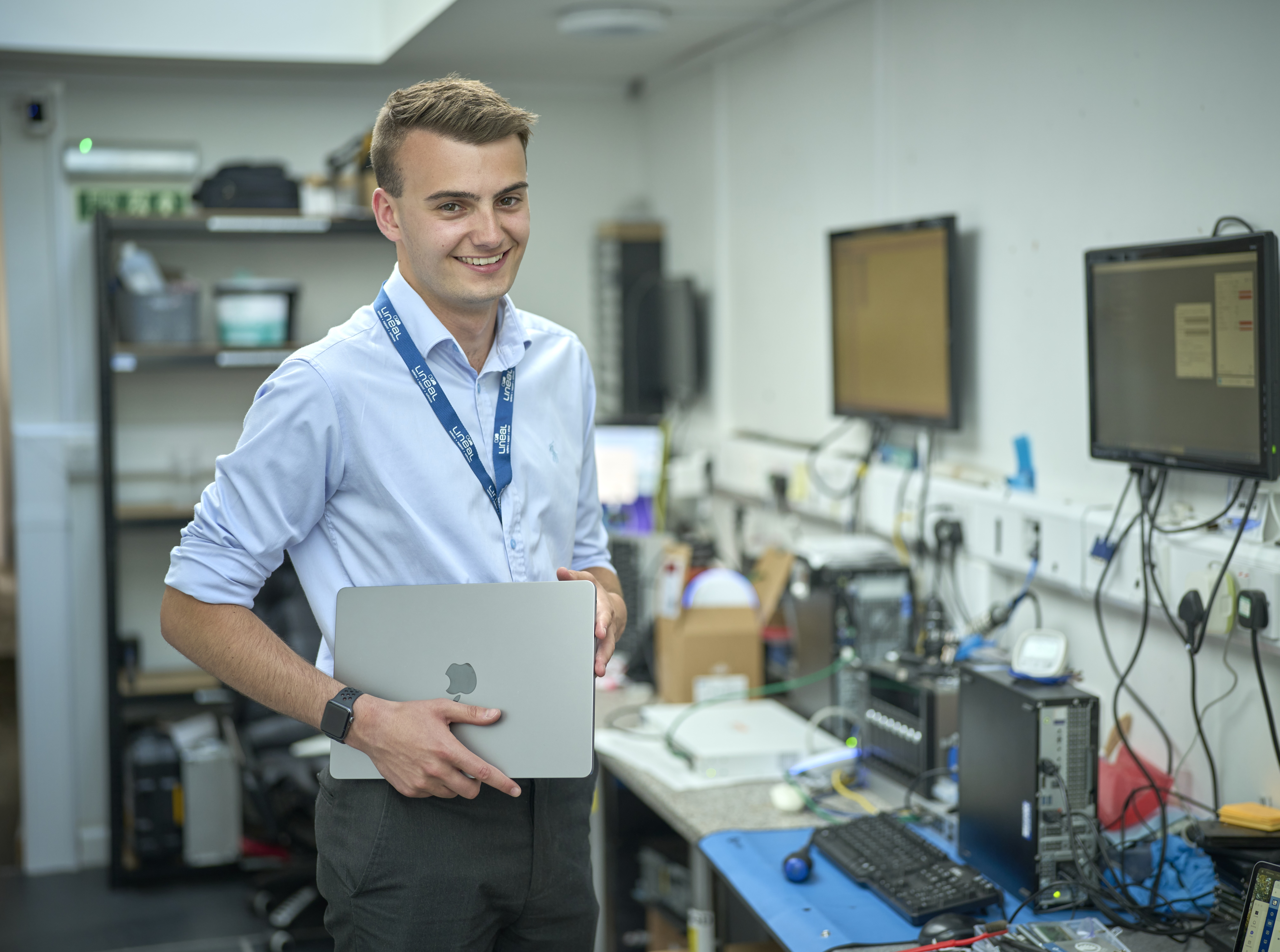 Alex in an office holding a laptop