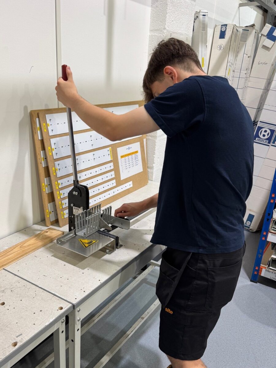 Luke operating a level-operated manual punch press in the workshop.