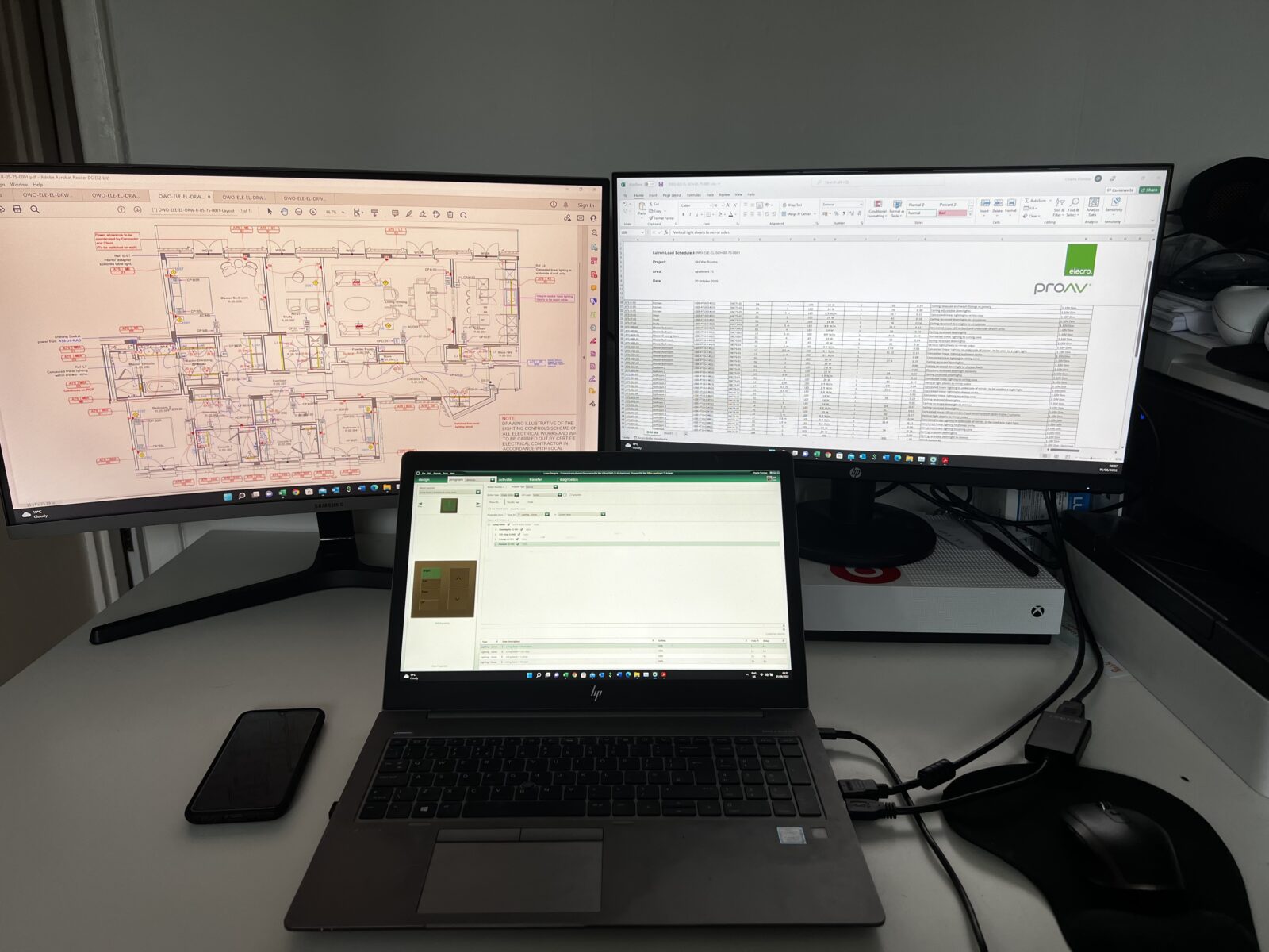 Laptop and 2 computer screens showing spreadsheet and building plans