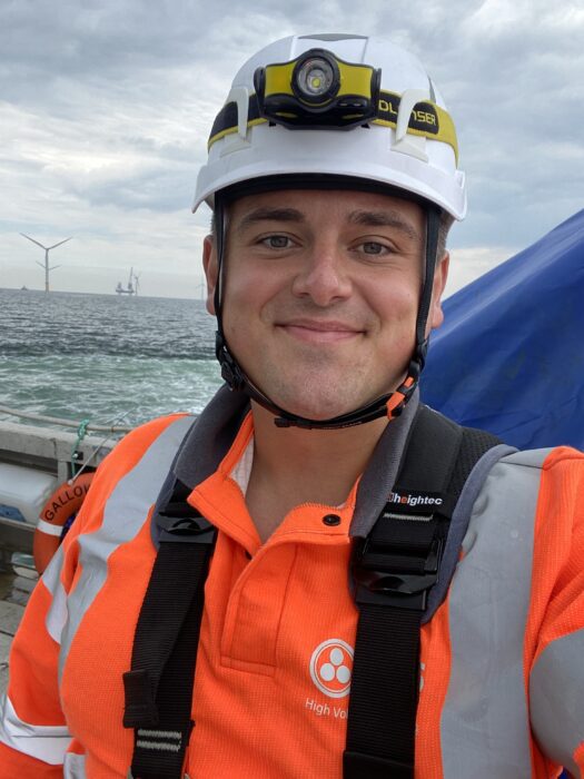 Man in hard hat and high vis out to sea at wind turbine plant