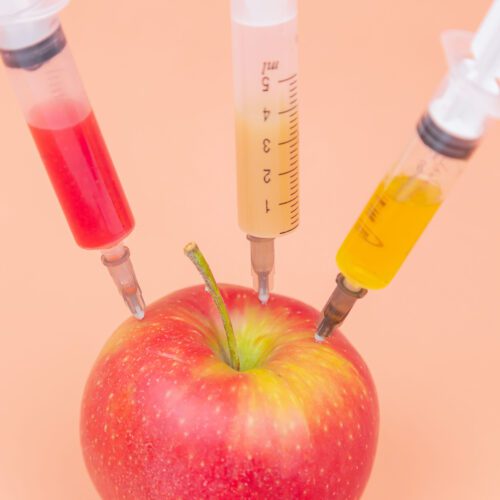 Apple with three syringes stuck in it