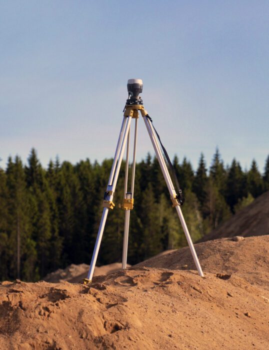 Surveying equipment on tripod overlooking forest