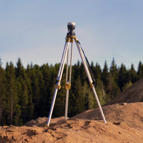 Surveying equipment on tripod overlooking forest